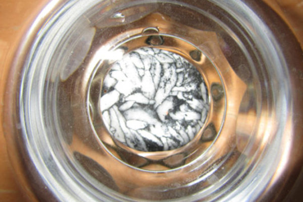 Photo d'une pierre de Pinolite dans un verre d'eau pour la nettoyer